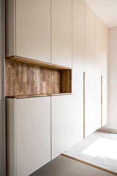 an empty room with white cupboards and wooden shelves