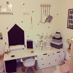 a white desk topped with lots of toys and decor next to a wall covered in polka dots