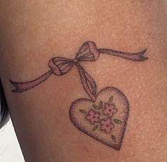 a heart tattoo with a bow and flowers on it