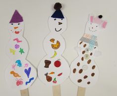 three snowmen made out of popsicle sticks sitting next to each other on a white surface