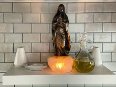 a candle and some bottles on a shelf in front of a wall with white tiles