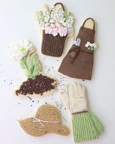 four decorated cookies in the shape of flowers and gardening gloves on a white table top