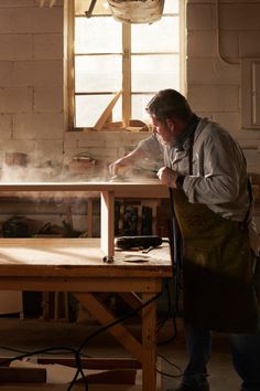 a man in an apron working on a wooden table