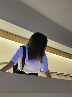 a woman standing on top of an escalator with her back to the camera