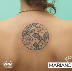 the back of a woman's shoulder with roses in a circle tattoo on it