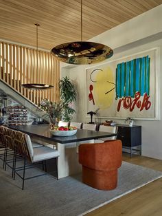 a dining room table and chairs with artwork on the wall