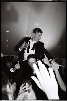 a man in a tuxedo is surrounded by people