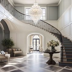 an elegant entryway with chandelier, chairs and table in front of the stairs