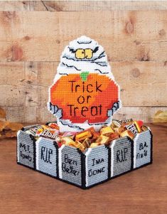 a trick or treat box with candy in it on top of a wooden table next to leaves