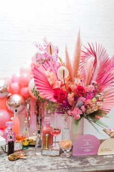 a table topped with lots of pink flowers and balloons