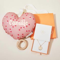 a pink heart shaped pillow with the word candile on it next to a wooden ring