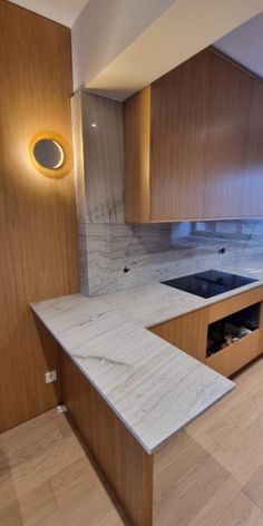 an empty kitchen with marble counter tops and wooden cabinetry, along with recessed lighting