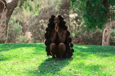 a woman sitting in the grass with her hands clasped to her face and eyes closed