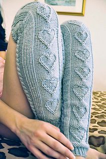 a woman laying on top of a bed wearing knitted socks