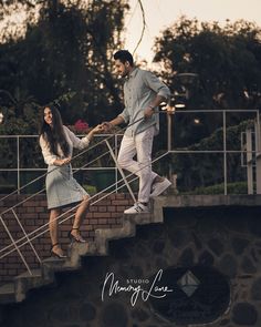 a man and woman walking up some stairs holding each other's hands as the sun sets behind them