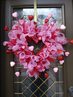 a heart - shaped wreath with pink and red hearts hanging from the front door frame