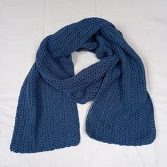 a blue knitted scarf laying on top of a white sheet