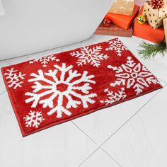 a red rug with white snowflakes on it next to presents and a bathtub