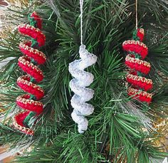 christmas ornaments hanging from a pine tree with red and white decorations on it's branches