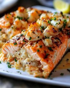 two pieces of salmon on a white plate with lemon wedges and parmesan cheese