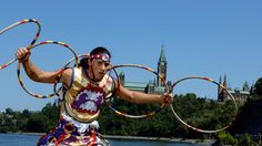 a man in costume is holding two hoop hula hoops while standing on the edge of a lake