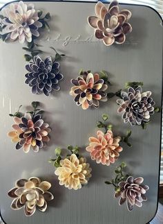 there are many different types of flowers on this metal tray, and each one is made out of paper