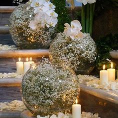 three vases filled with flowers and lit candles sitting on steps next to each other