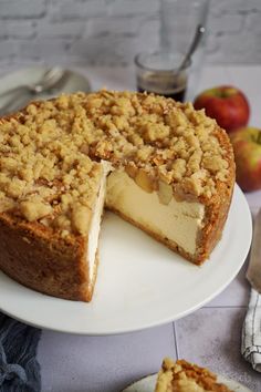 an apple crumb cake on a white plate with one slice missing from the pie