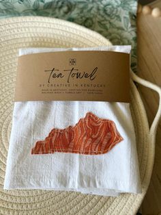 the tea towel is made from white linen with an orange and red print on it