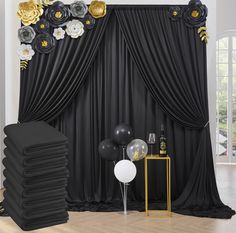 a room with black drapes, balloons and flowers on the wall next to it