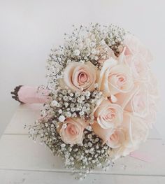 a bouquet of pink roses and baby's breath is sitting on a white table