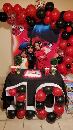 two children are standing in front of a table with balloons and decorations for an 10th birthday party