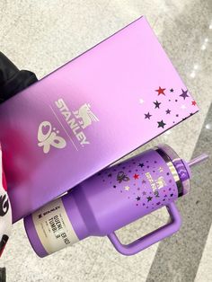 a person holding a purple water bottle in their left hand and a pink box with stars on it