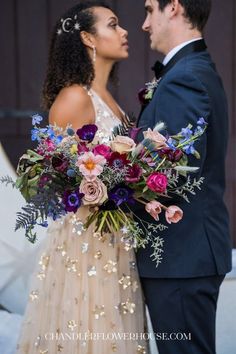 a bride and groom standing next to each other in front of a building with flowers