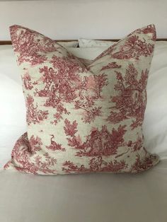 a red and white pillow sitting on top of a bed