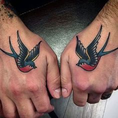 two hands with tattoos on them holding each other's fingers and one has a bird tattoo on it