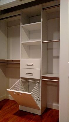 an empty closet is shown with white drawers and shelves on the bottom shelf, along with wooden flooring