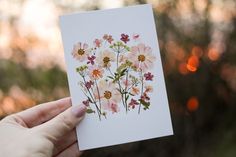 a person holding up a card with flowers on it