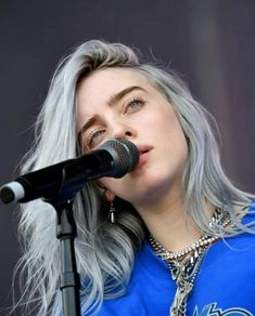 a woman with grey hair singing into a microphone