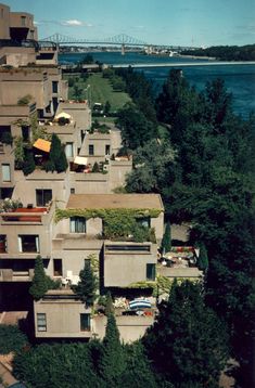 an aerial view of some apartment buildings with trees in the foreground and water in the background