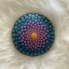 a painted rock sitting on top of a white fur covered floor with lots of dots