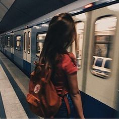 a woman with a backpack is waiting for the train to arrive at the subway station