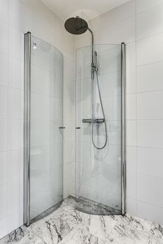 a bathroom with marble counter top and glass shower door, along with white tiles on the walls