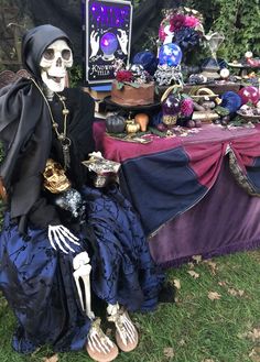 a skeleton sitting on top of a blue dress next to a table