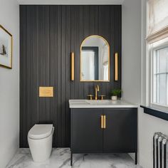 a white toilet sitting under a bathroom mirror next to a sink and radiator