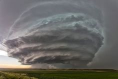 a large storm cloud looms over an open field