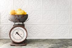 an old scale with lemons in it on a counter top next to a bowl of lemons