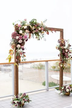 an outdoor ceremony setup with flowers and greenery on the side, overlooking the beach