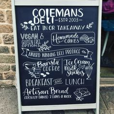 a chalkboard sign with different types of food on it's side, in front of a brick building