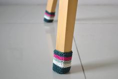 the legs of a wooden chair are decorated with multicolored yarn